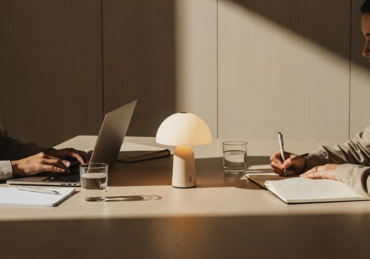 Two people across a desk in warm light